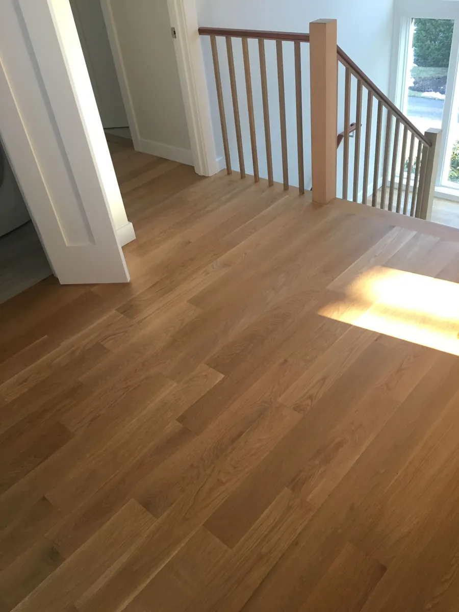 Natural oak floor installed across an upstairs landing beside a stair railing